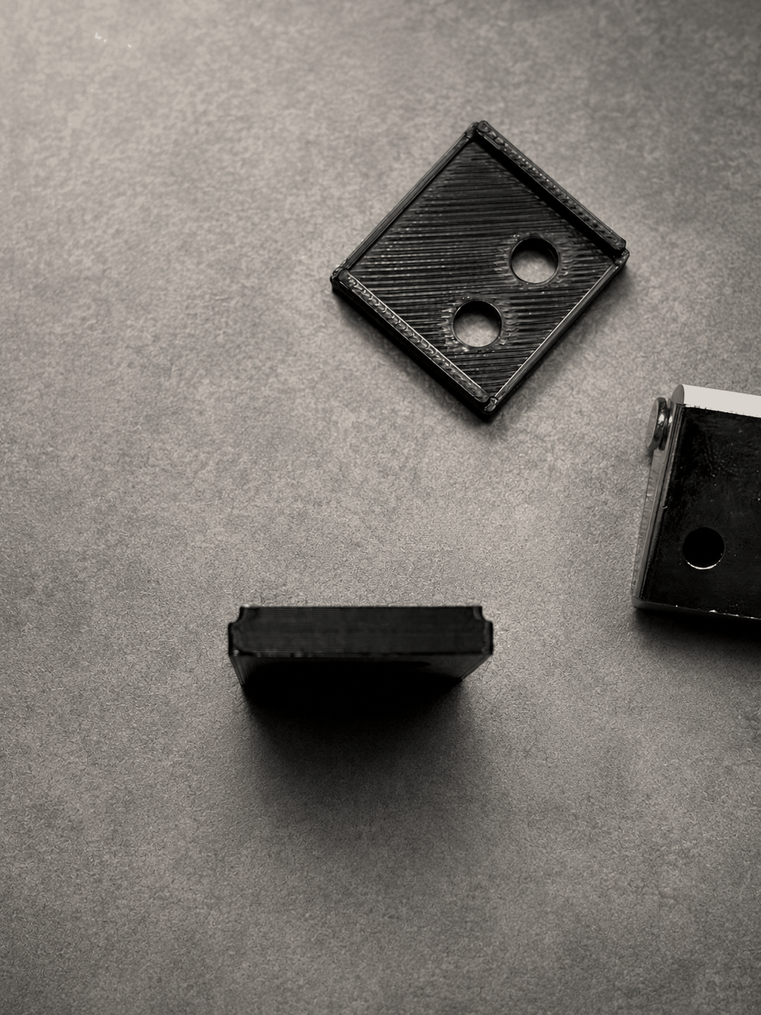 A black custom pocket-door bracket developed and printed by OliPoly.