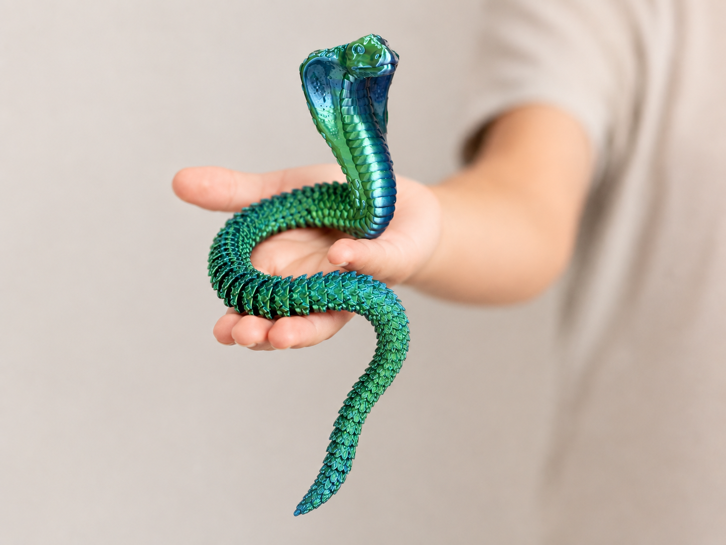 Iridescent cobra toy held in a hand