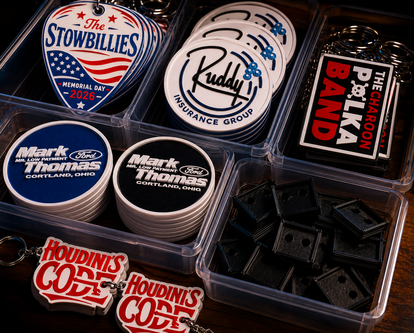 Organized bins of finished 3D printed coasters, keychains, branded pieces, and functional parts